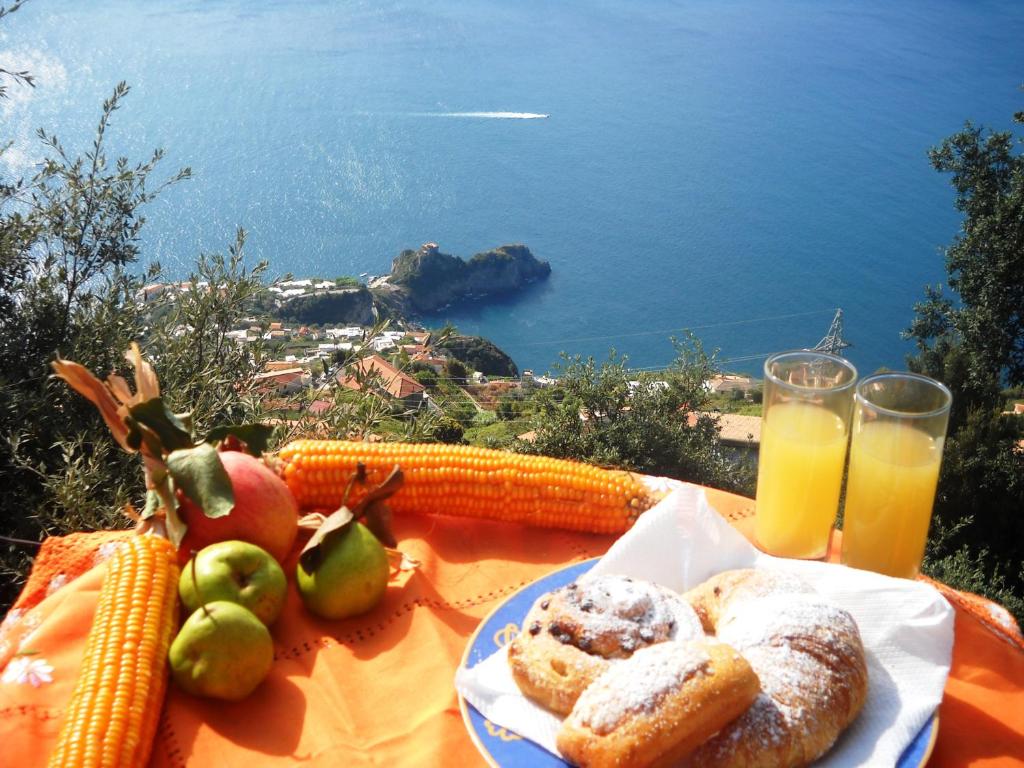 a table with a plate of bread and corn and orange juice at B&B Miramare in Agerola