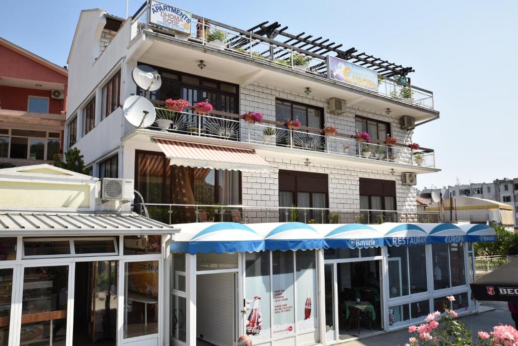 a white building with blue umbrellas in front of it at Guest House Evropa in Ulcinj