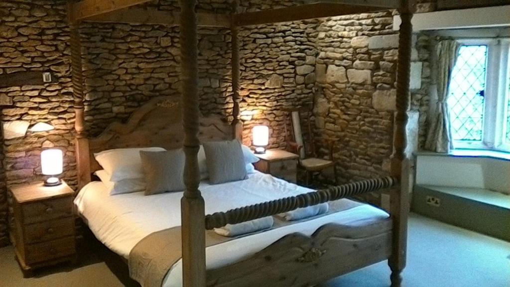 a bedroom with a bed in a stone wall at Swan Inn Lechlade in Lechlade