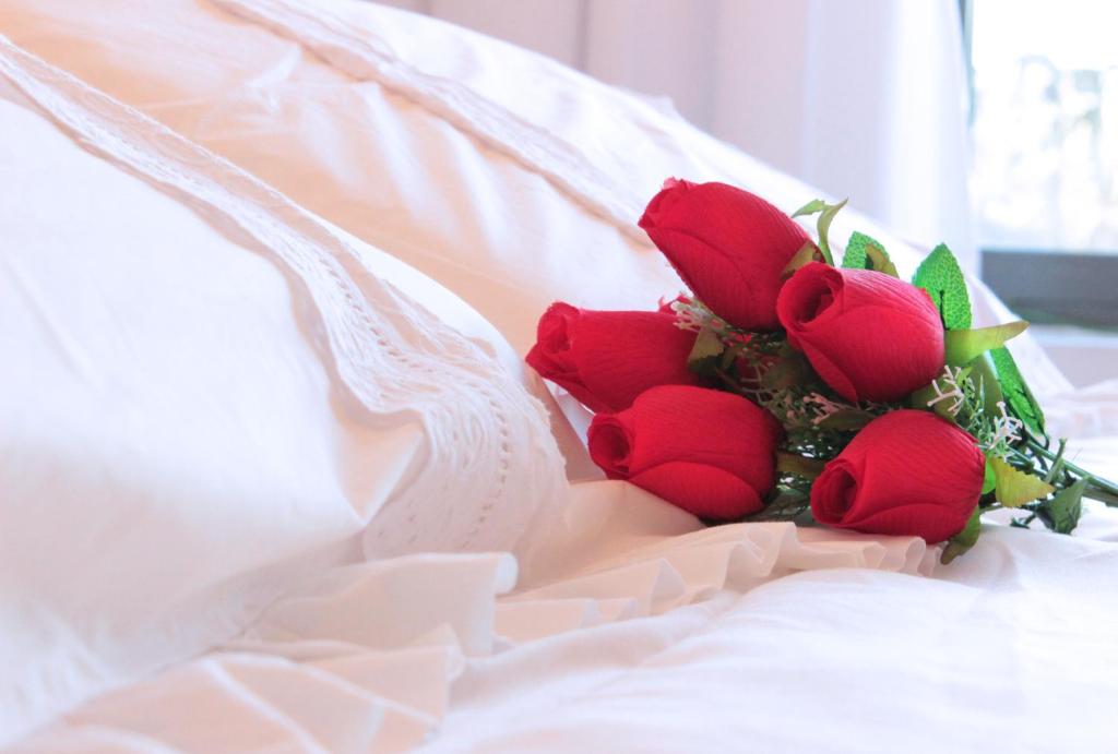 un grupo de rosas rojas sentadas en una cama en Residence Master Suite en Porteño Building en Buenos Aires