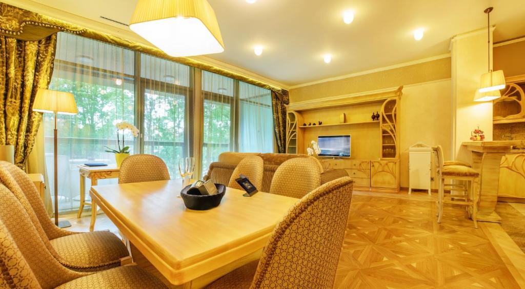 a dining room and living room with a table and chairs at Grand SPA Lietuva Serviced Apartments Dzūkija in Druskininkai