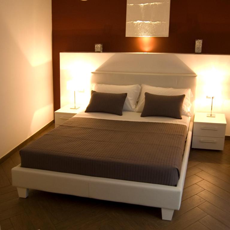 a bedroom with a large white bed with two lamps at Palazzo della Poesia Casa Vacanze in Salerno