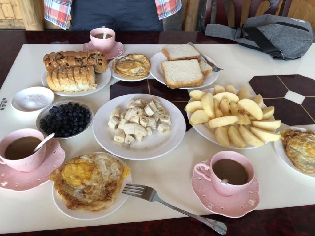a table topped with plates of food and cups of coffee at Yangjiajie Inn in Zhangjiajie