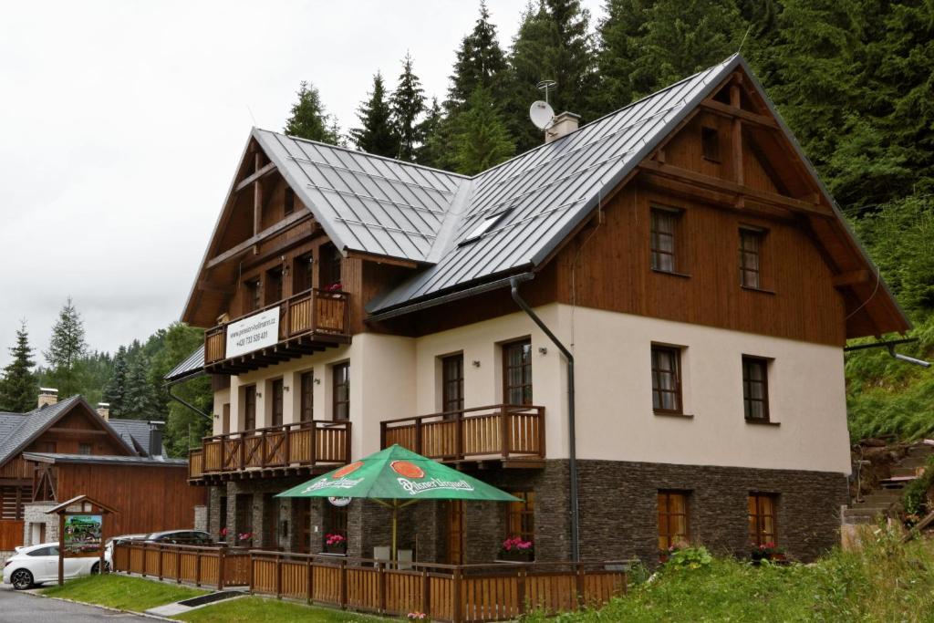 une maison avec un toit en gambrel et un balcon dans l'établissement Pension Hollmann, à Harrachov