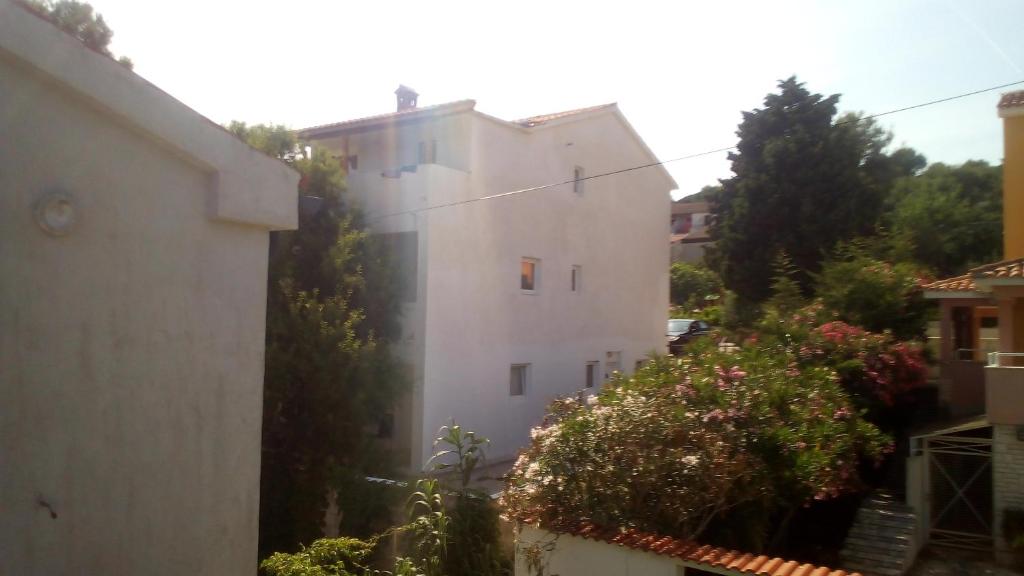 un edificio blanco con árboles y flores delante de él en Apartments and rooms Camelia, en Premantura