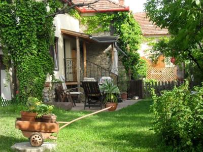 a house with a garden with a hose in the yard at Kőház apartman in Balatonfüred