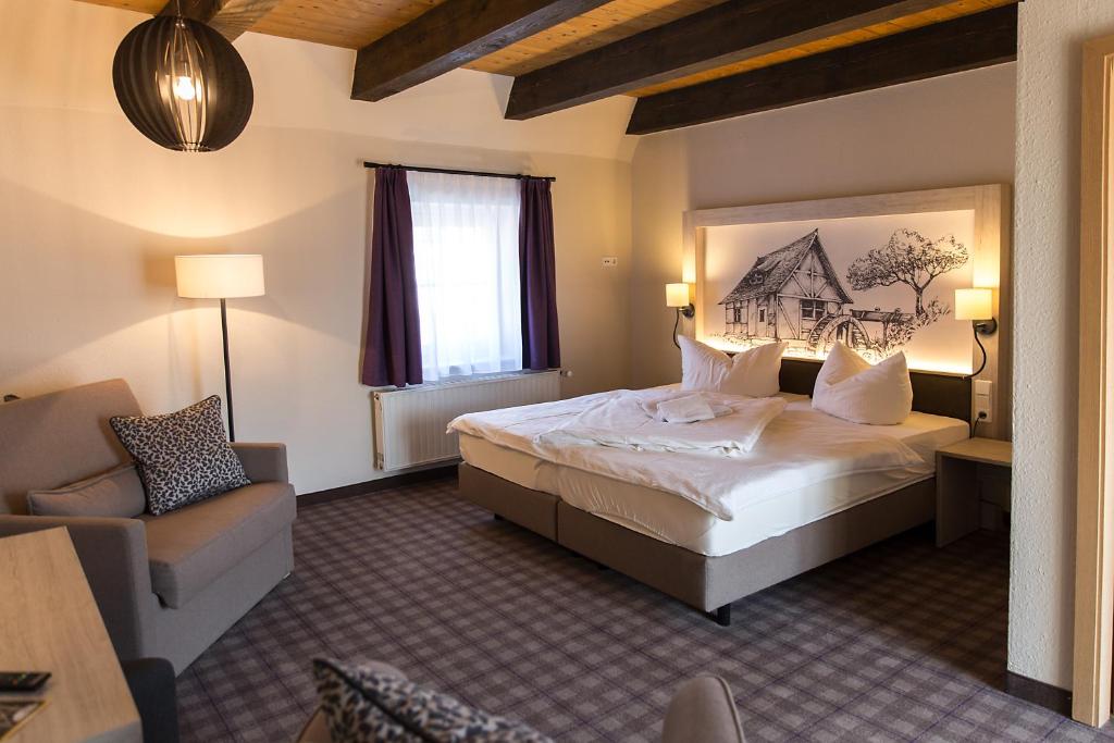 Habitación de hotel con cama grande y sofá en Hotel Garni Mühlenhof, en Wusterhausen