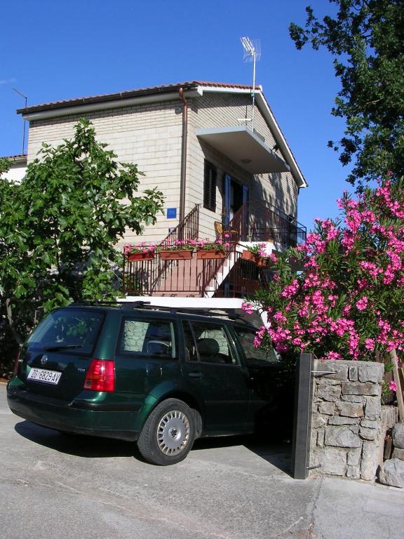 a green suv parked in front of a house at Apartment Perkovic Jadranka in Kornić