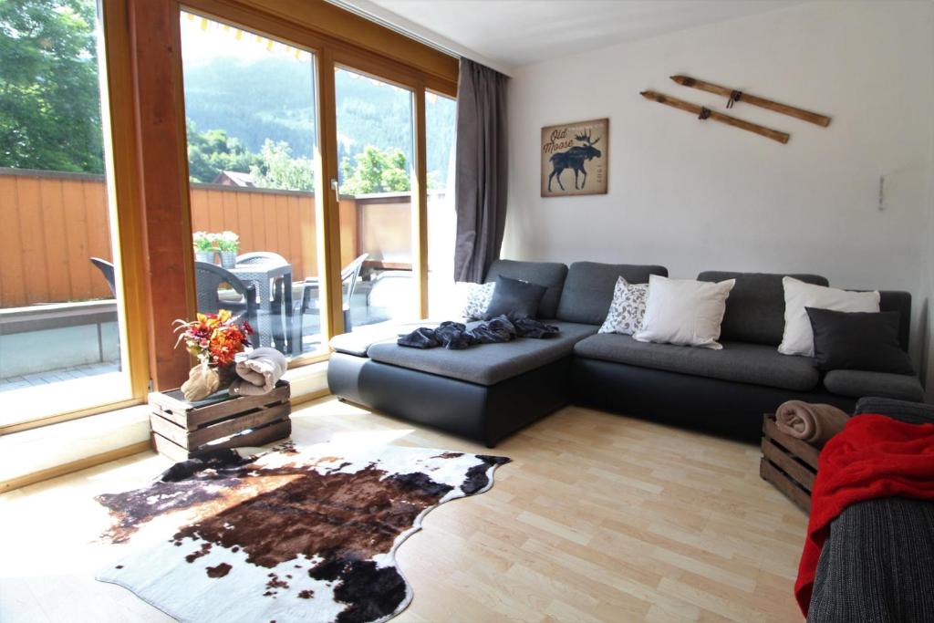 a living room with a black couch and a large window at FeWo Nicky by Isa Bad Kleinkirchheim in Bad Kleinkirchheim