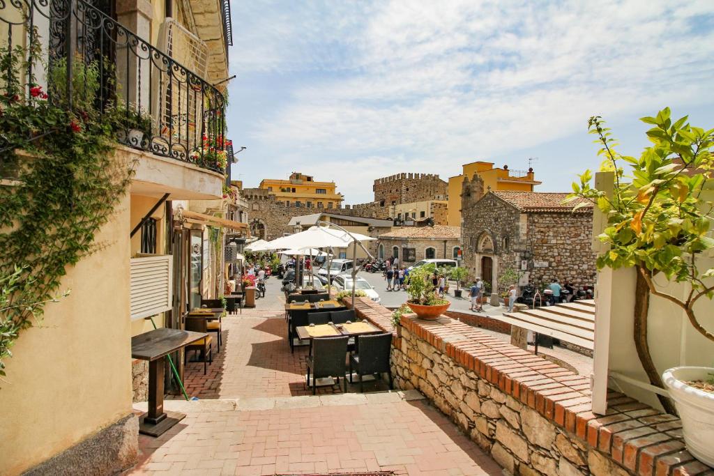 eine Stadtstraße mit Tischen, Stühlen und Gebäuden in der Unterkunft Taormina Sunny Experience in Taormina