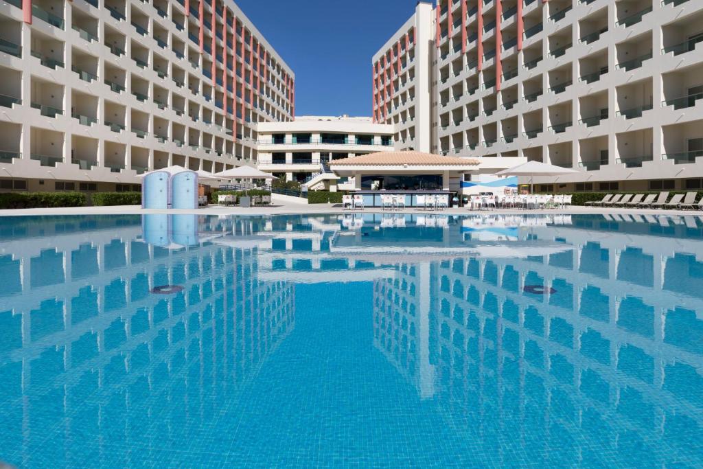 una gran piscina frente a dos edificios en Ukino Palmeiras Village - 24h All Inclusive, en Armação de Pêra