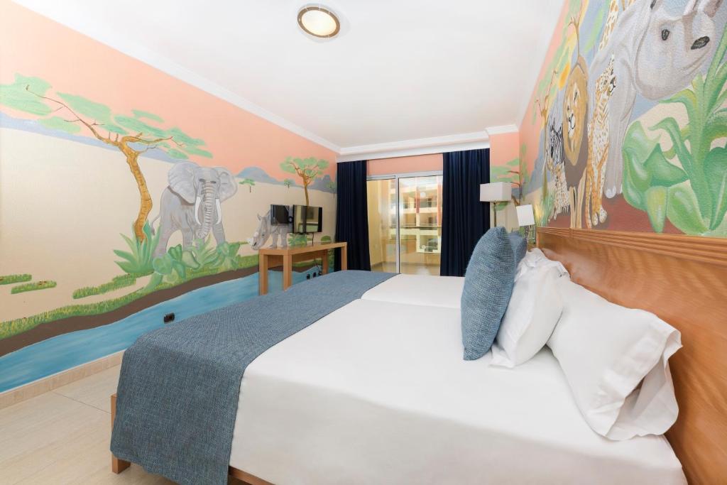 Un dormitorio con una cama con un cuadro en la pared. en Ukino Palmeiras Village - 24h All Inclusive, en Armação de Pêra