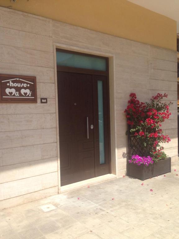 ポリニャーノ・ア・マーレにあるHouse Mamiの黒い扉と花の植物