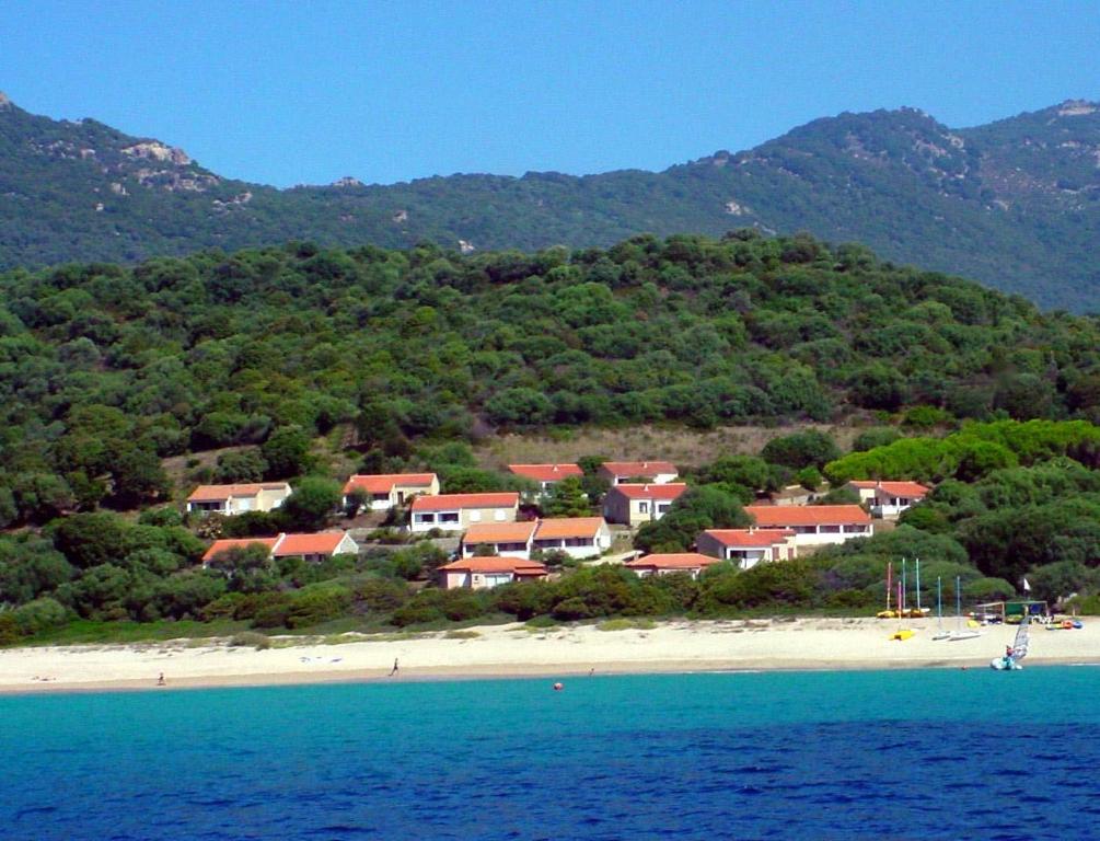 un gruppo di case su una spiaggia vicino all'acqua di Residence Capicciolo a Olmeto