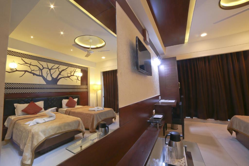a hotel room with two beds and a mirror at Hotel Grand Pragati in Surat