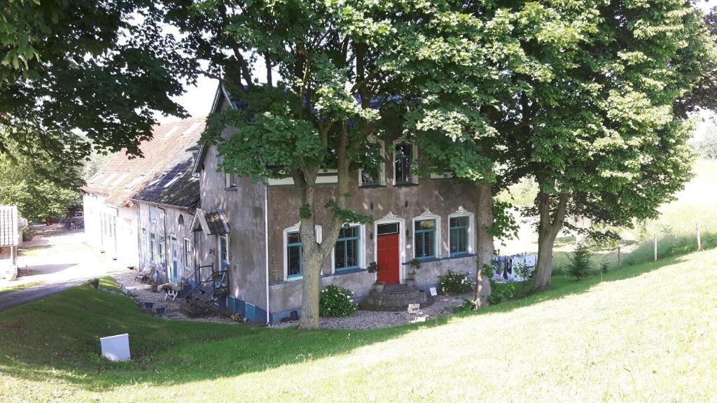 una casa vieja con una puerta roja en un patio en Theetuin Onder de Pannen, en Lekkerkerk
