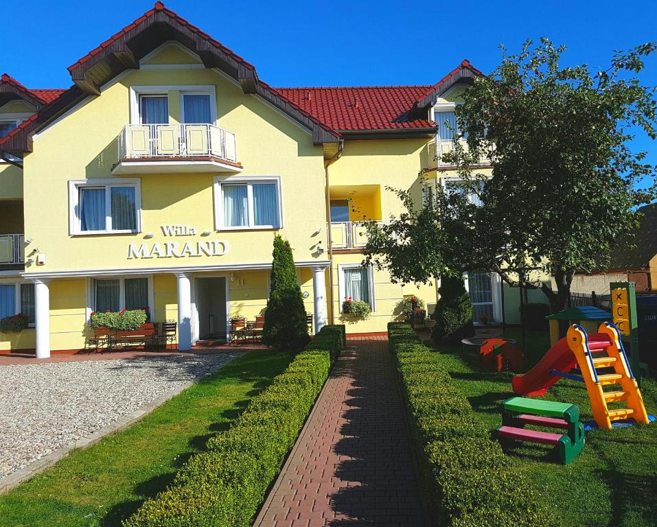 a yellow building with a playground in front of it at Willa Marand in Jastarnia