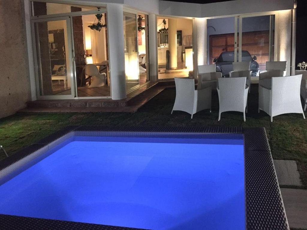 a swimming pool with blue lighting in a backyard at night at Stella Moresca Luxury Villa in Calasetta