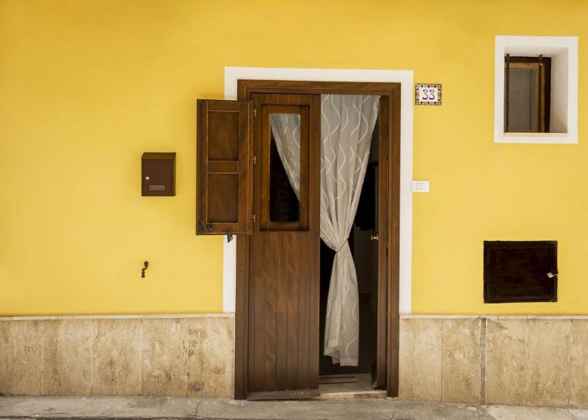 a wooden door in a yellow wall with a window at La Casuzza in Castellammare del Golfo