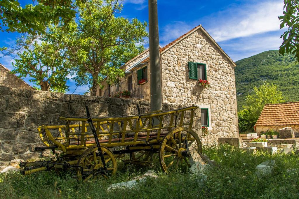 eine Holzbank vor einem Steingebäude in der Unterkunft Holiday Home Godinj in Donje Rašćane