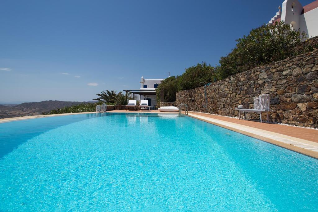 una piscina de agua azul y una pared de piedra en Panorea Complex - Mykonos, en Ano Mera