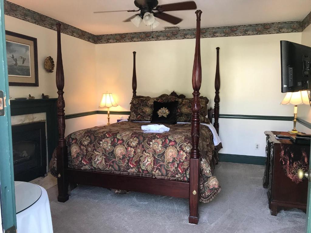 a bedroom with a canopy bed and a fireplace at Parsonage Inn Bed and Breakfast in Saint Michaels