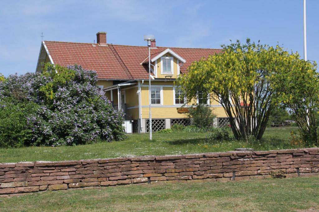 una casa amarilla con una pared de ladrillo y árboles en Klockaregården i Högsrum, en Högsrum