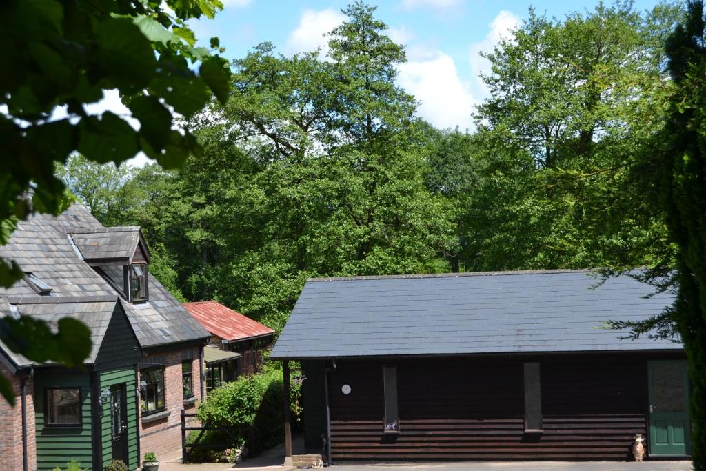 a house with a black roof and trees in the background at Arrowwood Self Catering (Wagtail and Nuthatch) in Kington