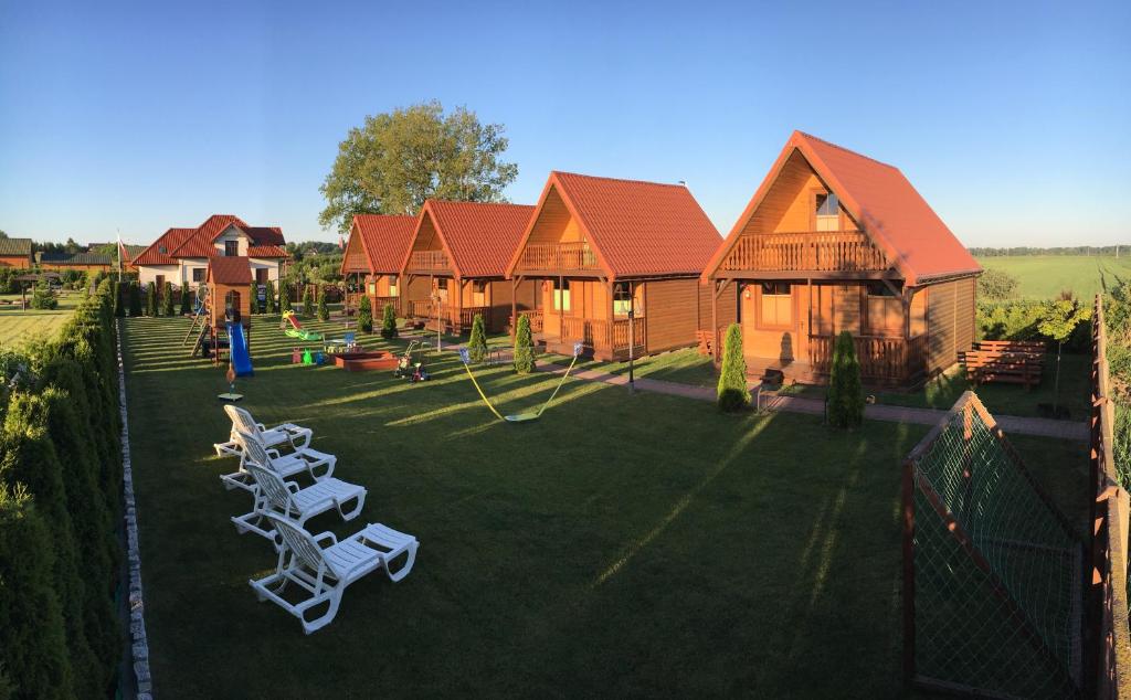 a group of chairs sitting on a lawn in front of a house at Domki letniskowe IWET in Darłowo