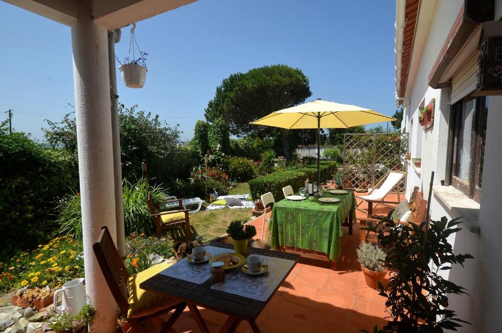 a patio with a table and a yellow umbrella at Happy Cat House - Holiday Rental in São Martinho do Porto