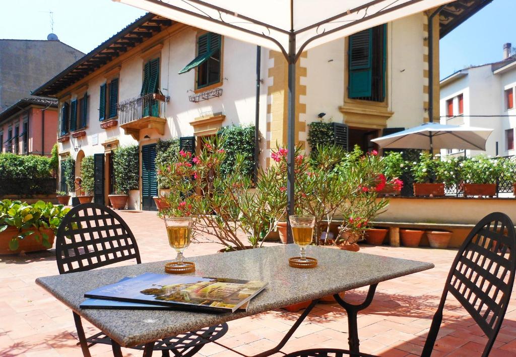 un tavolo esterno con due sedie e un ombrellone di Poggio Imperiale Apartments a Firenze