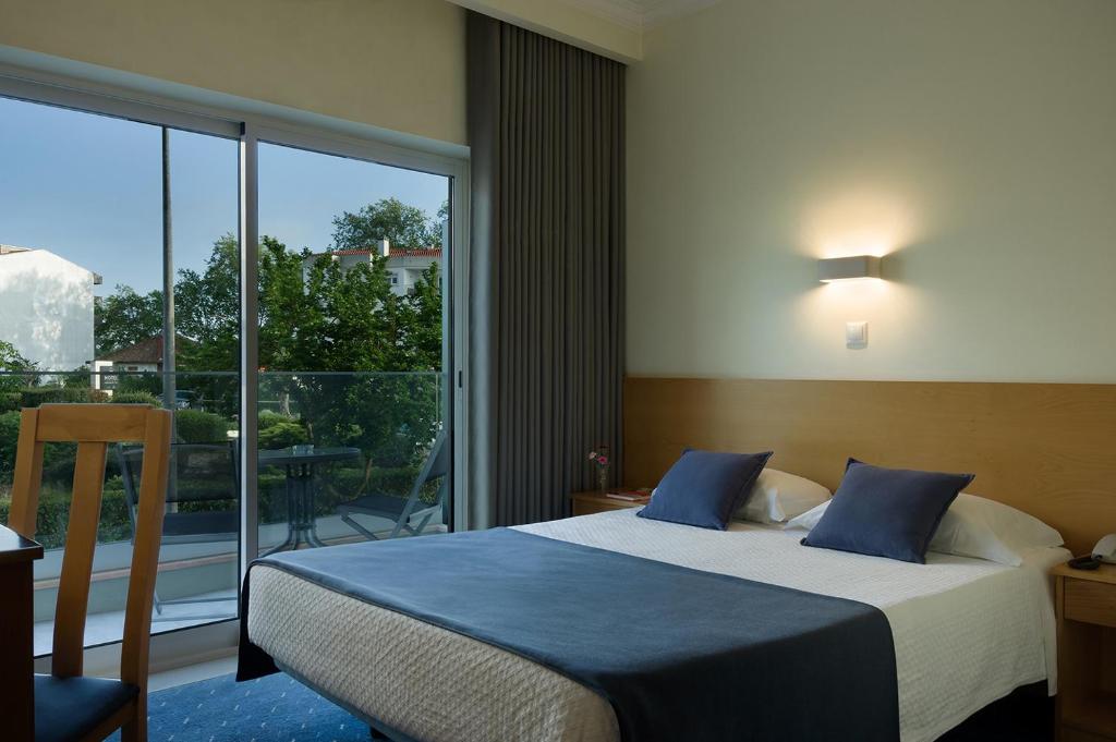um quarto com uma cama e uma grande janela em Cova da Iria Hotel em Fátima