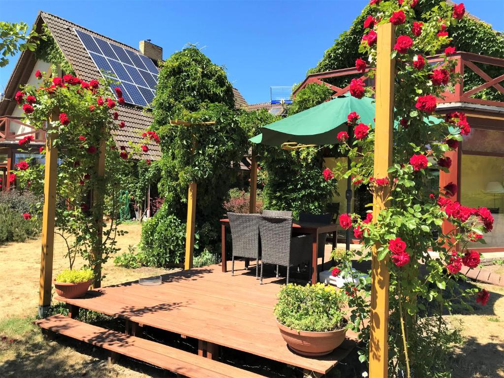 una terraza de madera con flores, una mesa y una sombrilla en Dom Pod Różą Wiatrów Lubin near Międzyzdroje Miedzyzdroje Misdroy, cisza, spokój, ruhig, peaceful, beautiful view en Międzyzdroje