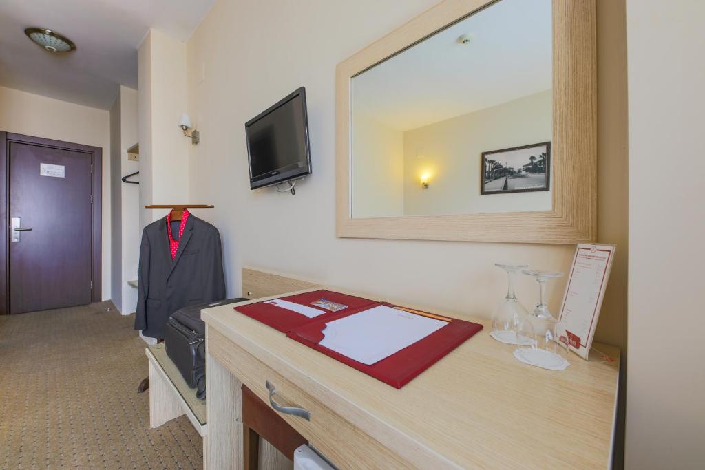 a room with a desk with a suit and a mirror at Hostapark Hotel in Mersin