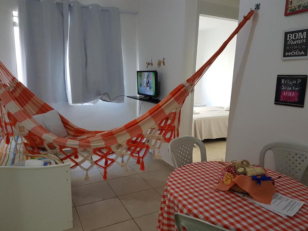 a room with a hammock and a table and a television at Apartamento no Dalas Park Residencial in Campina Grande