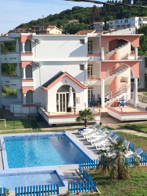 a villa with a swimming pool in front of a building at Guest House Green Garden in Ulcinj