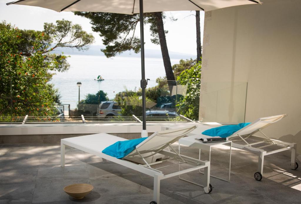 a patio with two chairs and a table and an umbrella at casa mare brela in Brela
