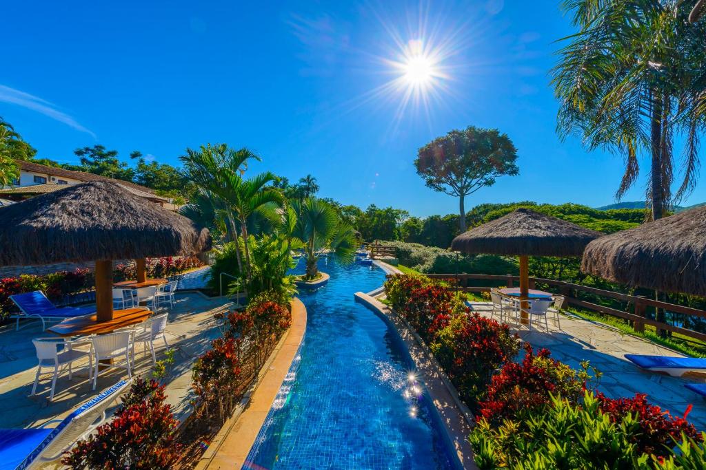 einen Pool in einem Resort mit Stühlen und Sonnenschirmen in der Unterkunft Pousada dos Pireneus in Pirenópolis