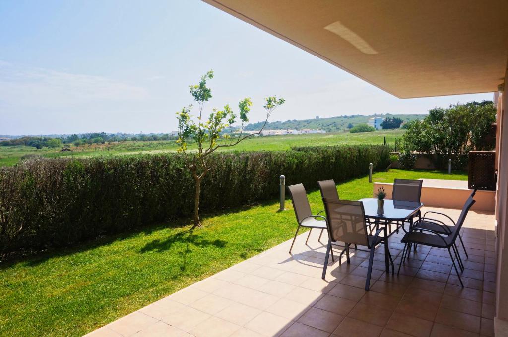 un patio con mesa, sillas y un campo en Casa Laranja, Aromas Burgau, en Burgau