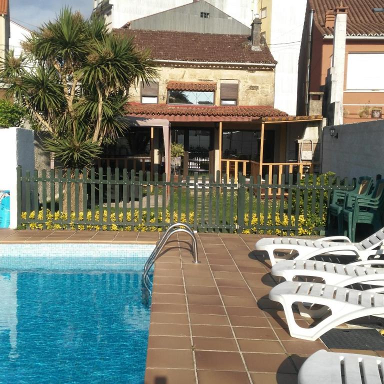 a swimming pool with lounge chairs next to a building at Casa Balbina in O Grove