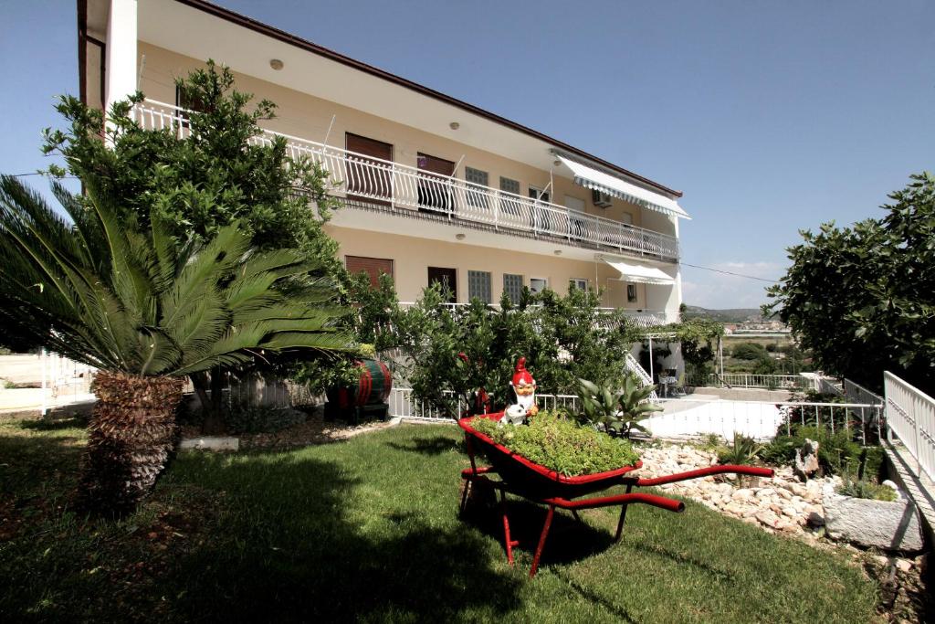 a garden in front of a building with a wheelbarrow at Apartment Carmen in Trogir