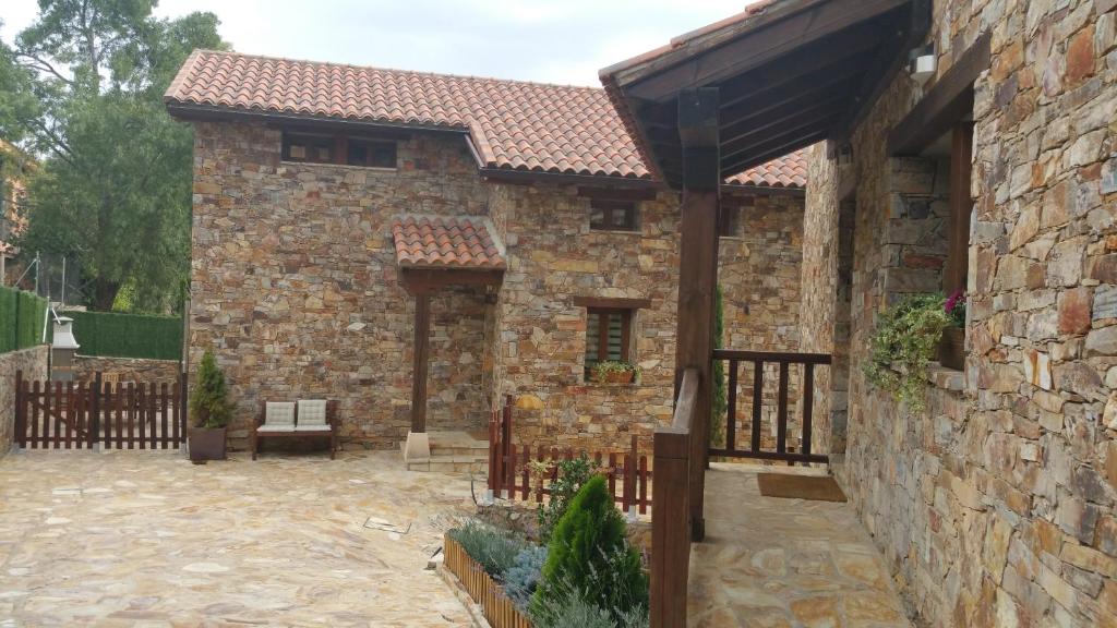 uma casa de pedra com uma cerca de madeira e um pátio em Nature Rural em Berzosa del Lozoya