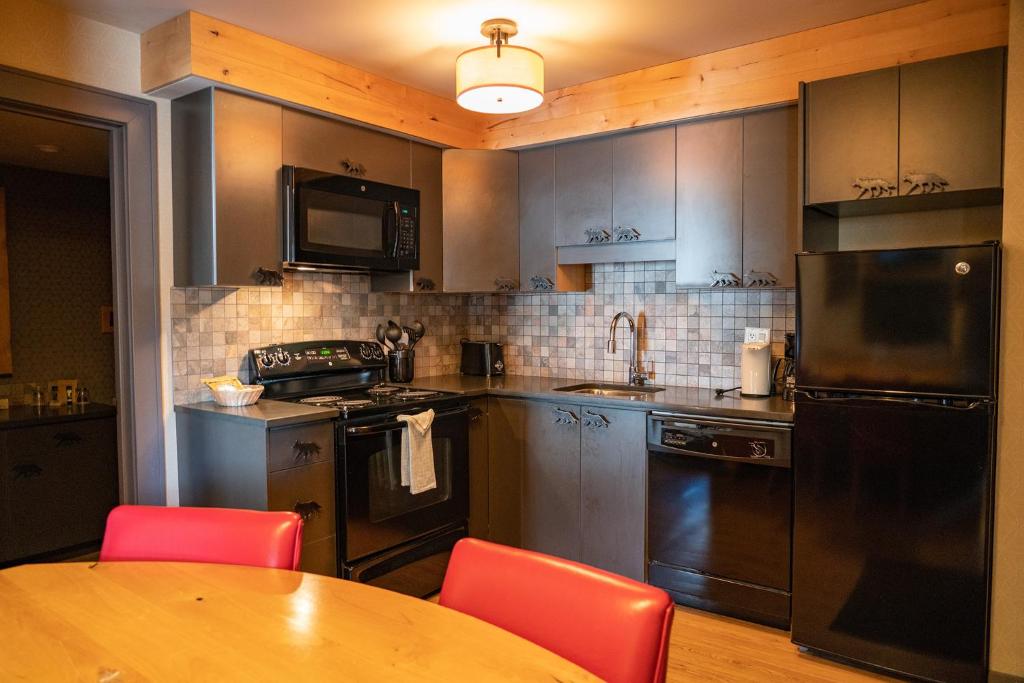 a kitchen with stainless steel appliances and a wooden table at Banff Rocky Mountain Resort in Banff