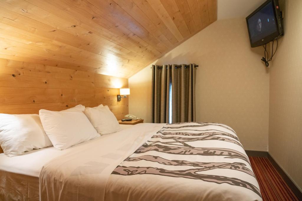 a bedroom with a large bed with a television on the wall at Banff Rocky Mountain Resort in Banff