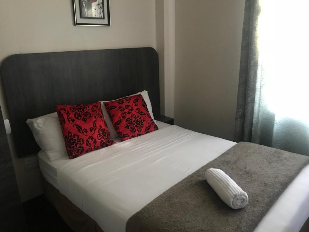 Una cama con dos almohadas rojas encima. en Businessburg Hotel en Johannesburgo