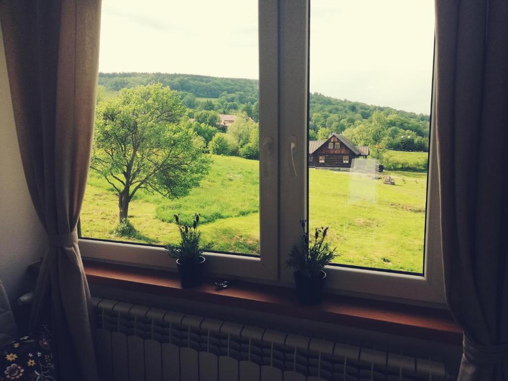 una ventana con vistas a un campo y un granero en Pokoje goscinne u Olguni, en Chyrowa