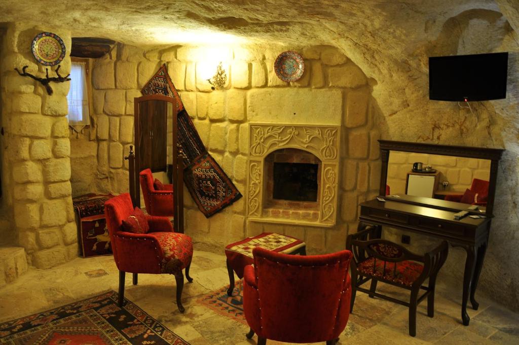 ウルギュップにあるネイチュレルス ケイブ ハウスの石造りの暖炉とピアノ付きのリビングルーム