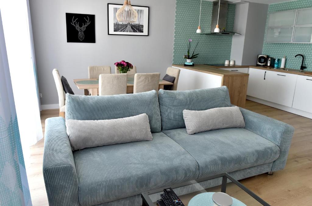 a living room with a blue couch and a kitchen at Apartament Turkus in Kościerzyna
