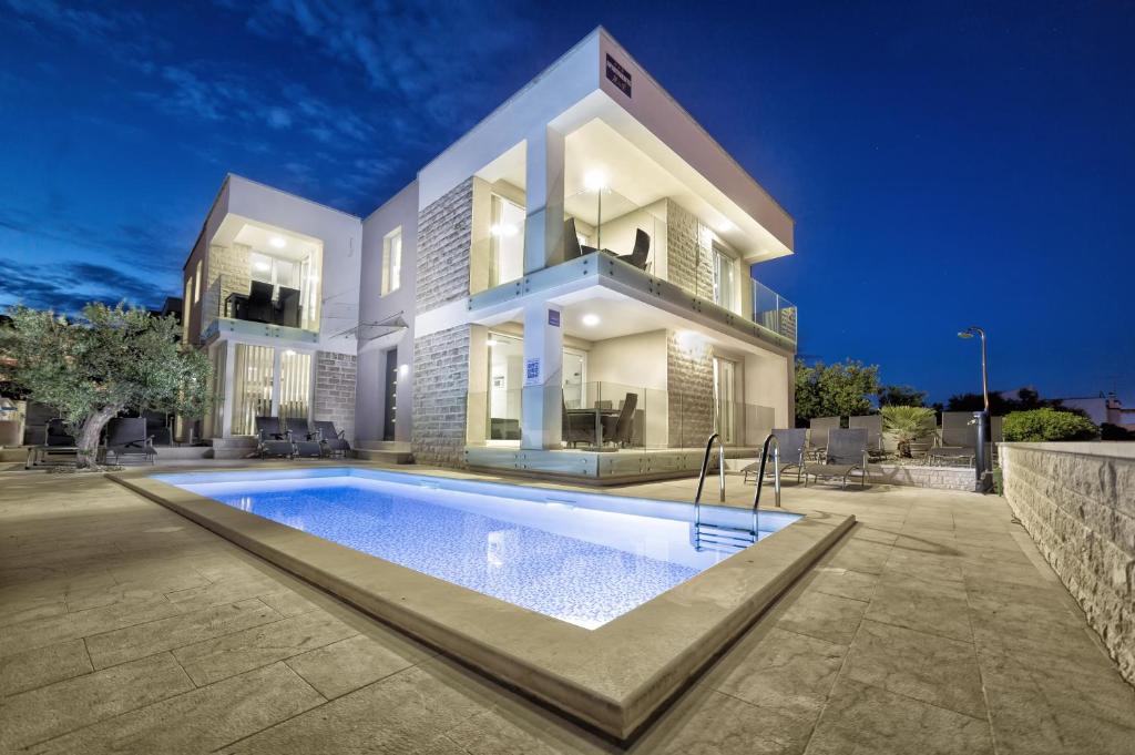 a house with a swimming pool in front of it at Apartments M&L in Vodice