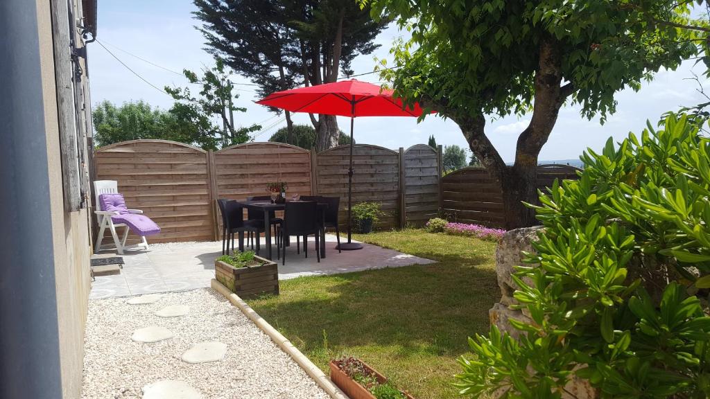 un patio con una mesa con una sombrilla roja en Domaine de la belle Lurette en Saint-Pierre-dʼAurillac